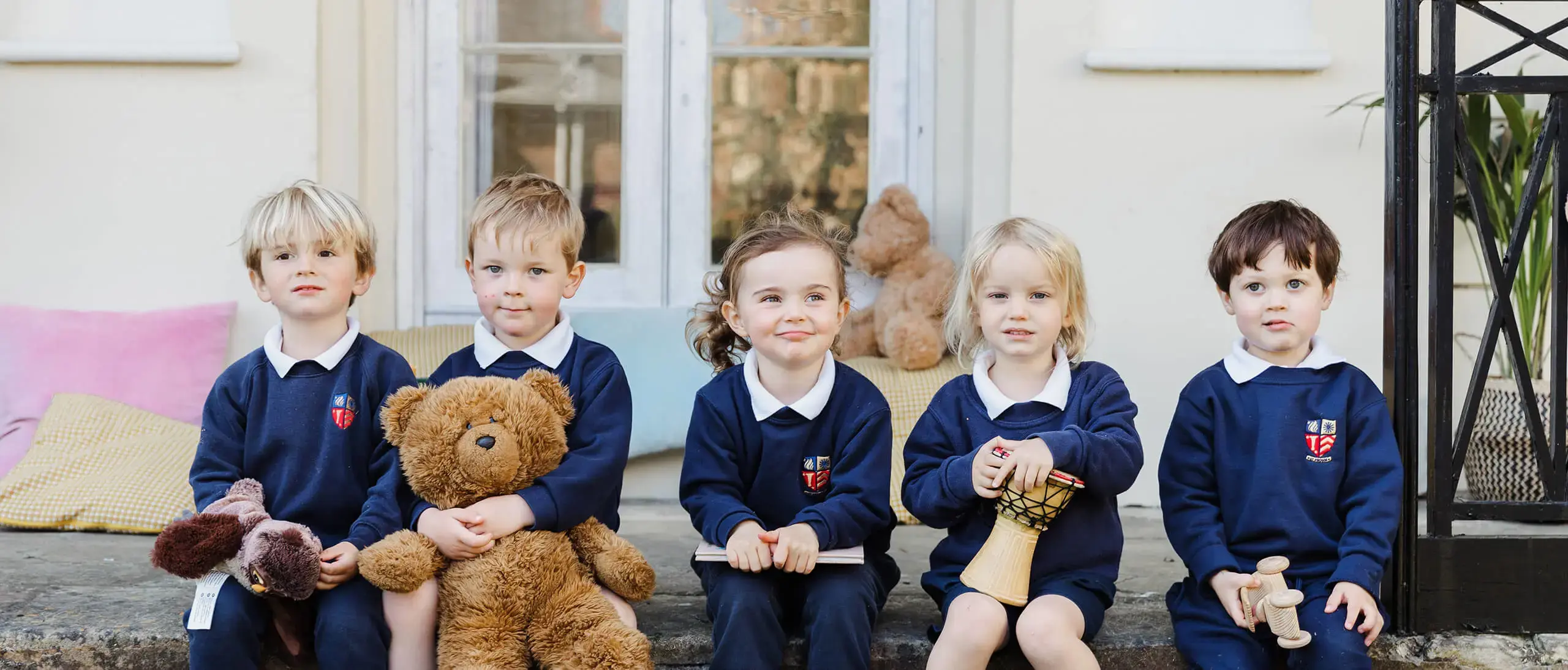 Westhill Nursery pupils sitting outside with books, toys, and musical instruments